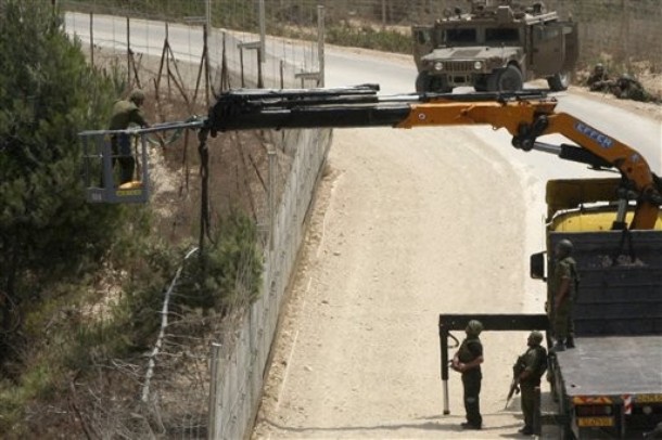 Israeli soldiers use a crane as they appear to cut a tree on the Lebanese side of the border in the southern village of Adaisseh, Lebanon, Tuesday, Aug. 3, 2010. Lebanese and Israeli troops exchanged fire on the border Tuesday in the most serious clashes since a fierce war four years ago, authorities said. A Lebanese officer spoke on condition of anonymity under military guidelines, said the clash occurred as Israeli troops tried to remove a tree from the Lebanese side of the border