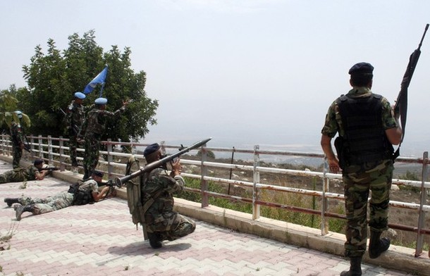 Lebanese soldiers take up position as U.N peacekeepers (in blue berets) gesture towards Israeli soldiers at the Lebanese-Israeli border in Adaisseh village, southern Lebanon August 3, 2010. An Israeli helicopter on Tuesday fired two missiles at a Lebanese army post near the southern border village of Adaisseh, destroying an armoured personnel carrier, a security source said. A Lebanese journalist and three Lebanese soldiers died after the Israeli and Lebanese armies exchanged fire in the border area, a security source said.