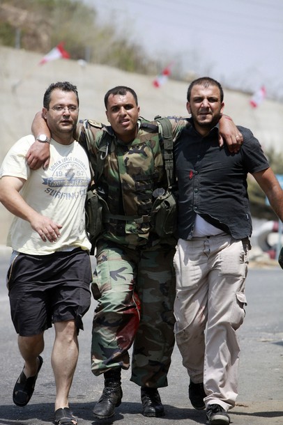 Civilians help a wounded Lebanese soldier at Adaisseh village, southern Lebanon August 3, 2010. An Israeli helicopter on Tuesday fired two missiles at a Lebanese army post near the southern border village of Adaisseh, destroying an armoured personnel carrier, a security source said. A Lebanese journalist and three Lebanese soldiers died after the Israeli and Lebanese armies exchanged fire in the border area, a security source said