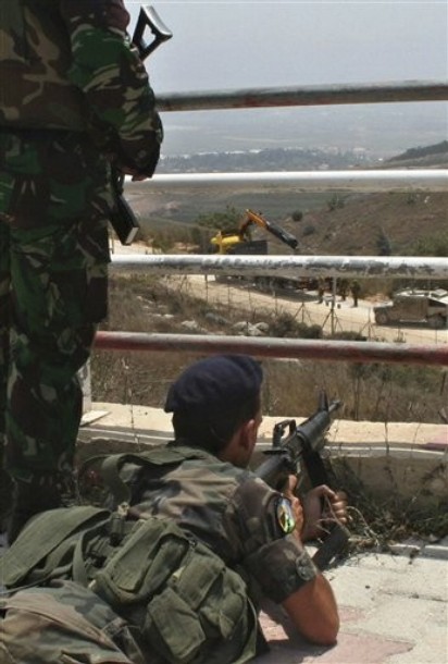 A Lebanese soldier holds his rifle as Israeli troops patrol the border fence in the southern border village of Adaisseh, Lebanon, Tuesday, Aug. 3, 2010. Lebanon and Israeli troops exchanged fire on the border Tuesday in the most serious clashes since a fierce war four years ago.