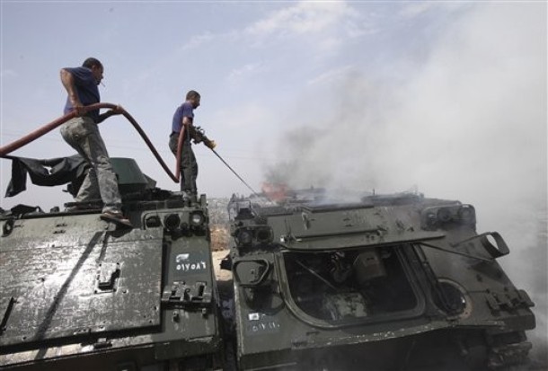 Lebanese civil defense workers extinguish a burning armored vehicle at a Lebanese army base in the southern border village of Taibeh, Lebanon, Tuesday, Aug. 3, 2010. Lebanon and Israeli troops exchanged fire on the border Tuesday in the most serious clashes since a fierce war four years ago, and Lebanon said at least two of its soldiers were killed in shelling, authorities said.