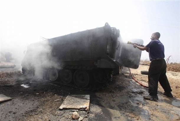 A Lebanese civil defense worker extinguishes a burning armored vehicle at a Lebanese army base in the southern border village of Taibeh, Lebanon, Tuesday, Aug. 3, 2010. Lebanon and Israeli troops exchanged fire on the border Tuesday in the most serious clashes since a fierce war four years ago